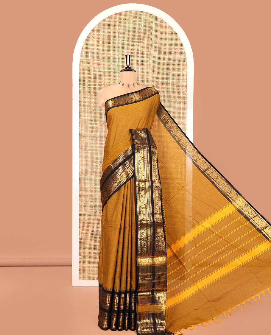 Mustard Plain Chettinad Cotton Saree, Complemented by a Contrast Rettai Pettu Temple Bright Gold Zari Border of Coin, Elephant, and Peacock Designs, Subtly Striped Pallu, and Paired with a Matching Blouse