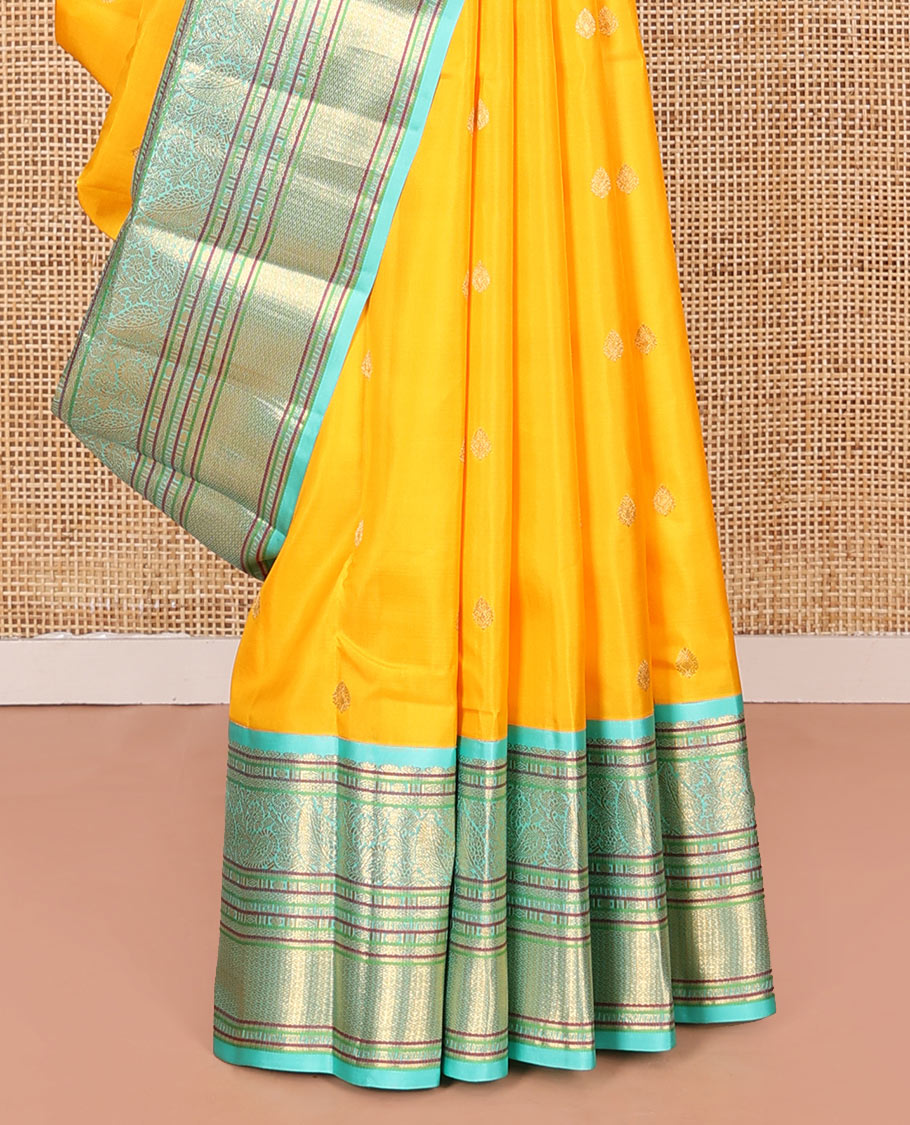 Yellow Vasundhara Silk Saree Decorated with Zari Buttas All Over Its Body, Complemented by a Contrast Border of Leaf, Rudraksham, Diamond, and Mayil Kann Designs, Pallu Featuring Manga Creeper Designs, and Paired with a Contrast Blouse