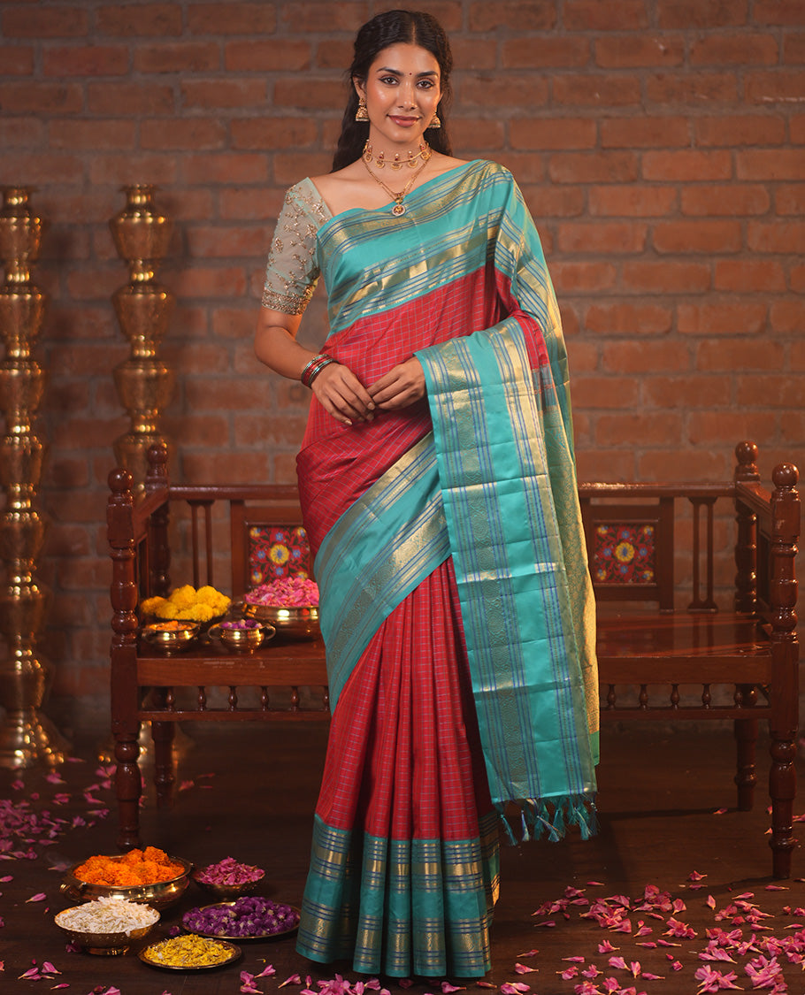 Tomato Red and Blue Vasundhara Silk Saree, Subtly Sparkled With Pattu Nool Kattam On Its Body, Complemented by Contrast Rettai Pettu Border of Salngai, Muthu, Neli, Rudraksham, and Dhavana Kodi Designs, Grand Pallu and Paired with a Contrast Blouse