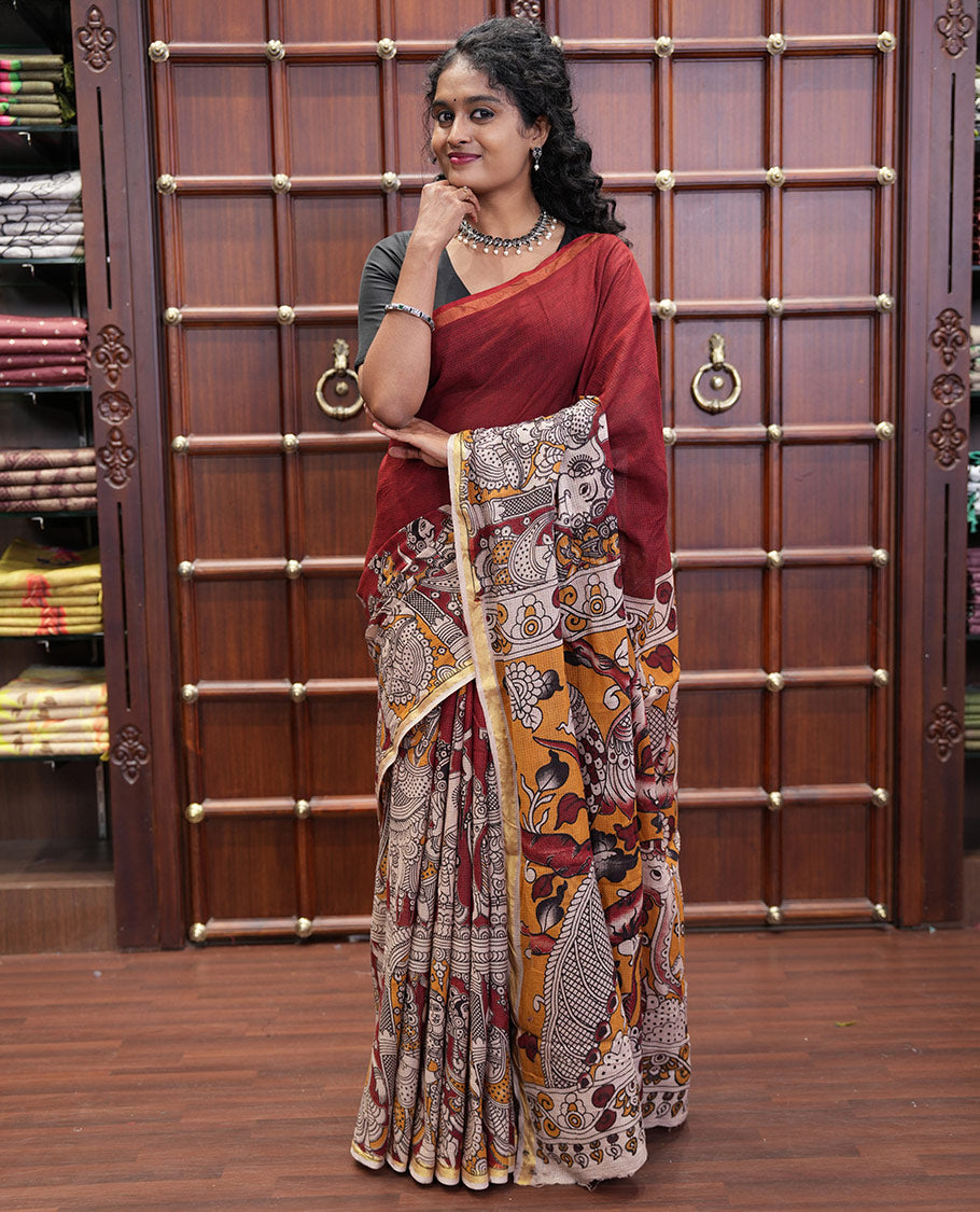 Maroon Kota Cotton Saree, Artfully Decked Up with Kalamkari-Style Human Figurines Printed on the Body, Subtle Piping Border, Pallu Pictures Kalamkari-Style Flora-Fauna Motifs, and Paired with a Contrast-Printed Blouse