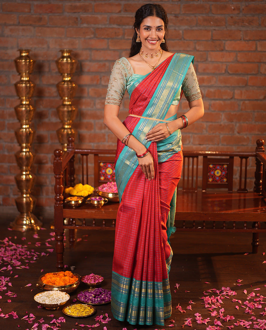 Tomato Red and Blue Vasundhara Silk Saree, Subtly Sparkled With Pattu Nool Kattam On Its Body, Complemented by Contrast Rettai Pettu Border of Salngai, Muthu, Neli, Rudraksham, and Dhavana Kodi Designs, Grand Pallu and Paired with a Contrast Blouse