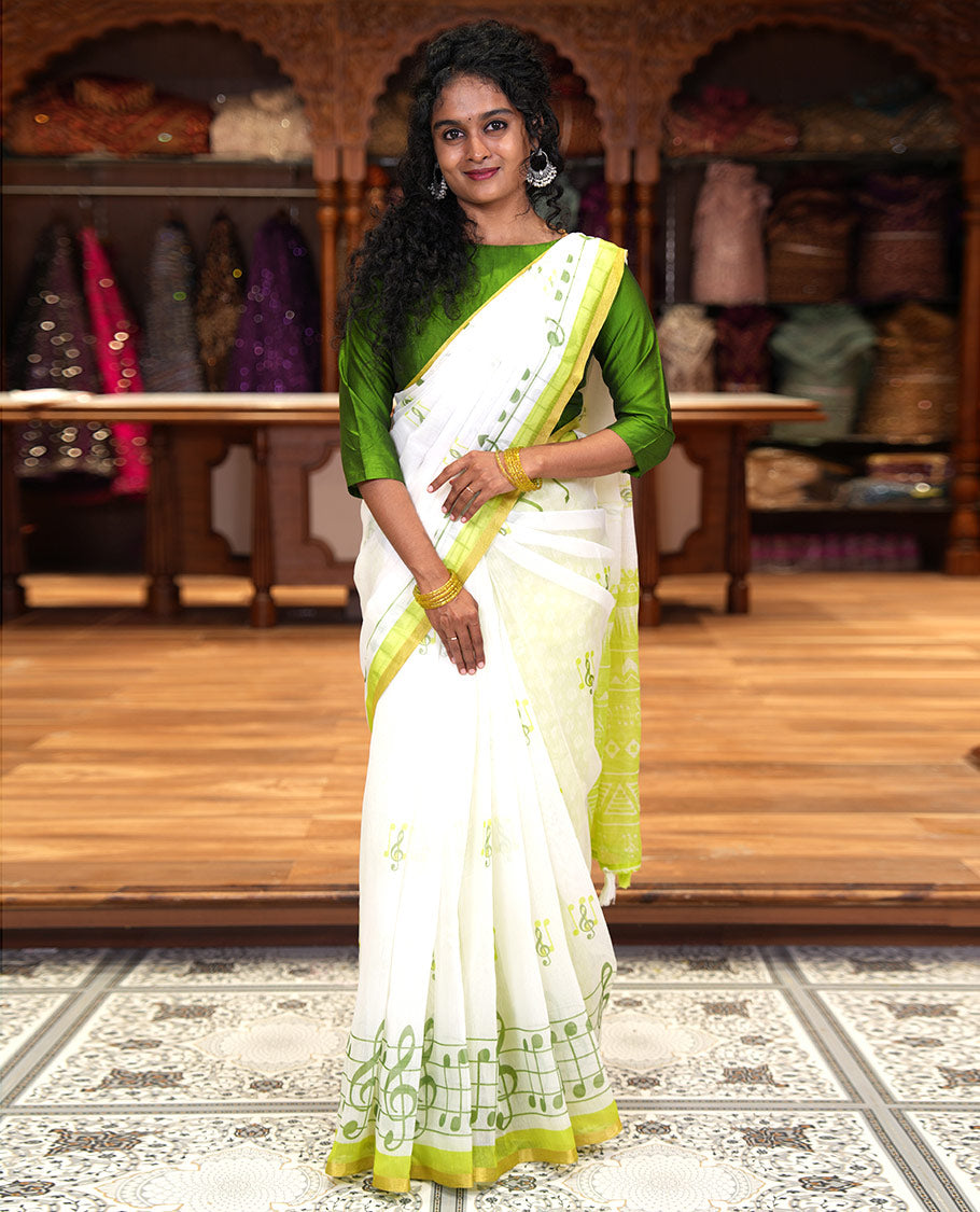 White and green musical note motifs printed Chanderi cotton saree, zari piping border, geometric printed pallu, and a unique motifs printed blouse