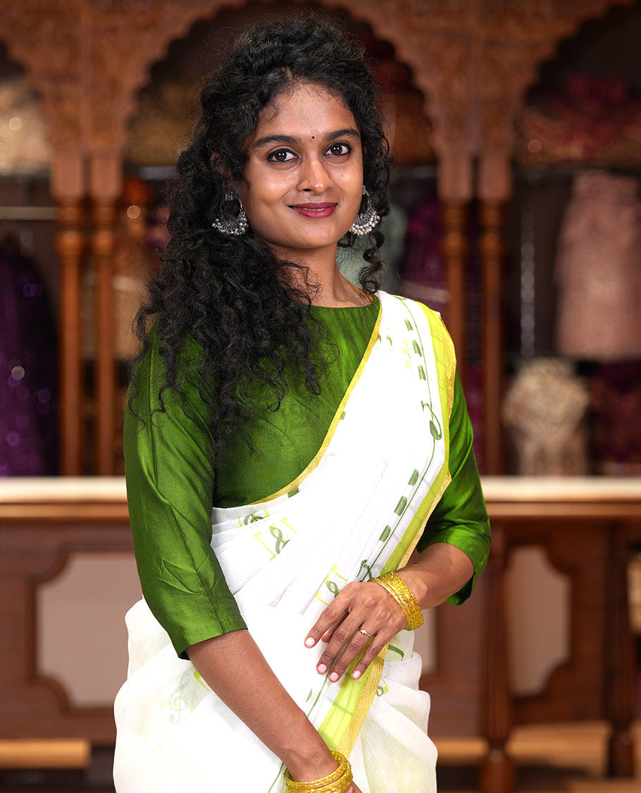 White and green musical note motifs printed Chanderi cotton saree, zari piping border, geometric printed pallu, and a unique motifs printed blouse