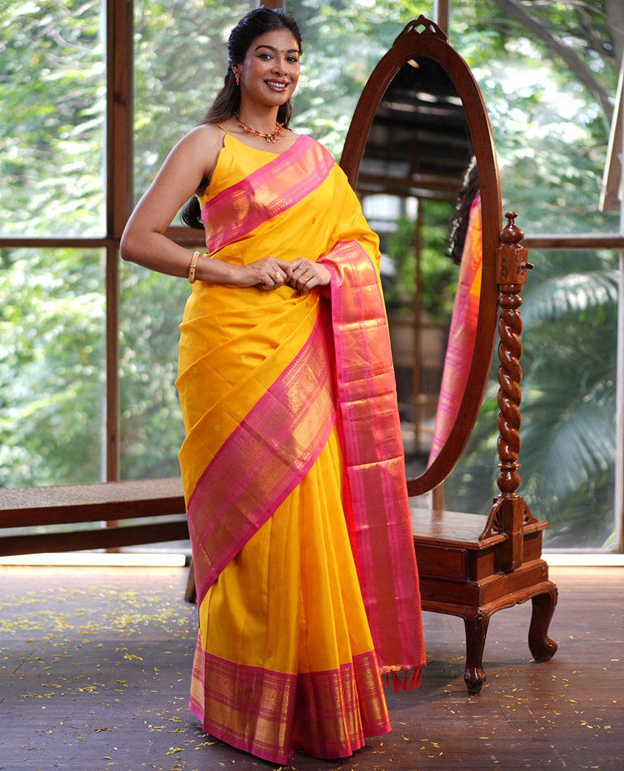 Mango Yellow Vasundhara Silk Saree, Subtly Sparkled with Sparse Stripes and Zari Buttas, Complemented by a Contrast Border of Thilakam, Banaras, Muthu, and Round Mayil Designs, Pallu Steeped with Traditional Designs, and Paired with a Contrast Blouse