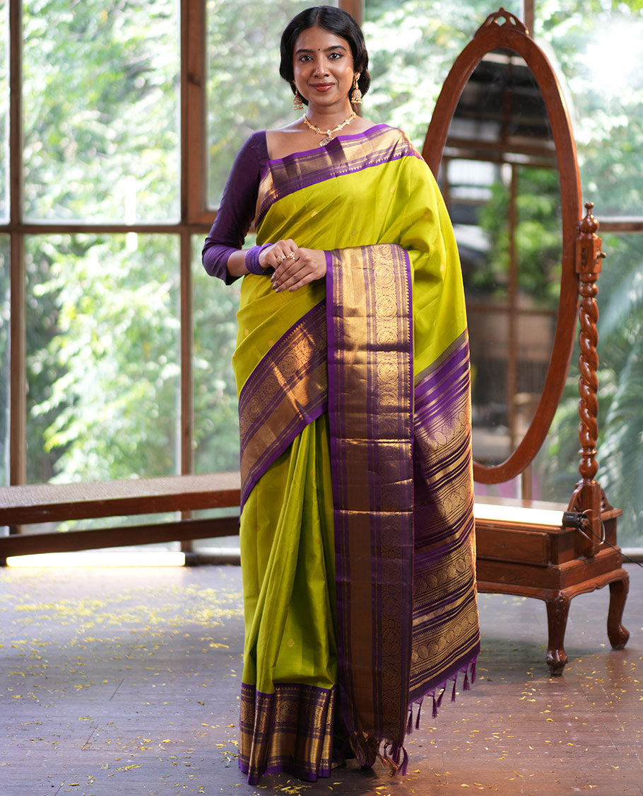 Parrot Green Vasundhara Silk Saree, Enriched with Sparse Stripes and Zari Buttas, Complemented by a Contrast Border of Thilakam, Banaras, Muthu, and Round Mayil Designs, Pallu Steeped with Traditional Designs, and Paired with a Contrast Blouse
