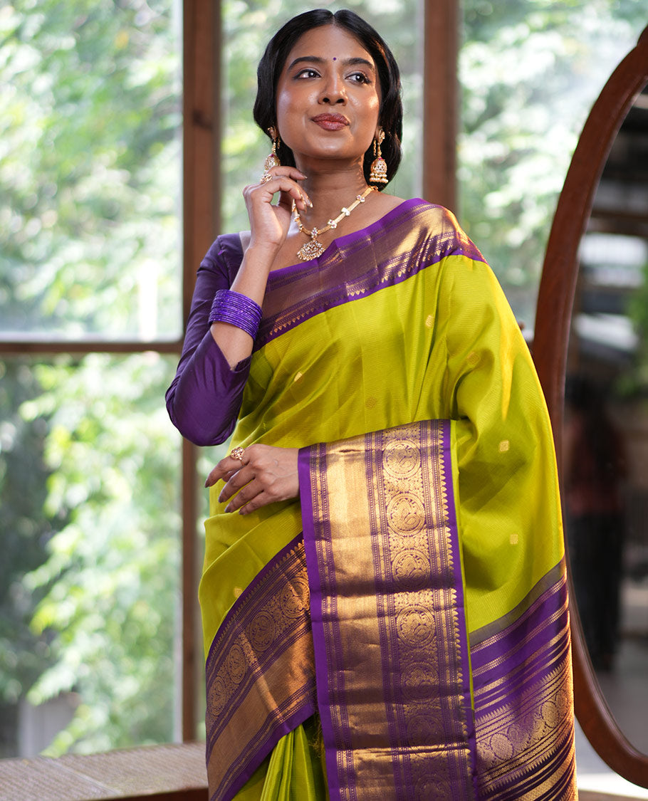 Parrot Green Vasundhara Silk Saree, Enriched with Sparse Stripes and Zari Buttas, Complemented by a Contrast Border of Thilakam, Banaras, Muthu, and Round Mayil Designs, Pallu Steeped with Traditional Designs, and Paired with a Contrast Blouse