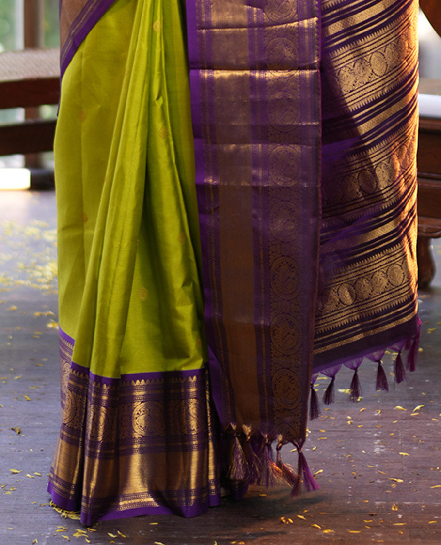 Parrot Green Vasundhara Silk Saree, Enriched with Sparse Stripes and Zari Buttas, Complemented by a Contrast Border of Thilakam, Banaras, Muthu, and Round Mayil Designs, Pallu Steeped with Traditional Designs, and Paired with a Contrast Blouse