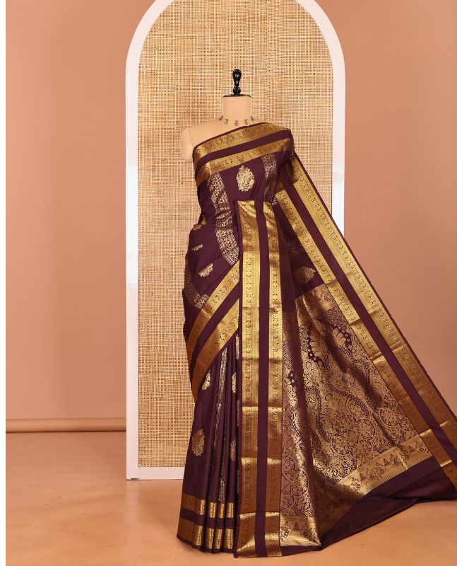 Brown Kanchipuram budget silk saree elevated with zari designs all over its body, complemented by rettai pettu traditional zari design border, Mughal-style intricately woven pallu, and paired with a Matching blouse