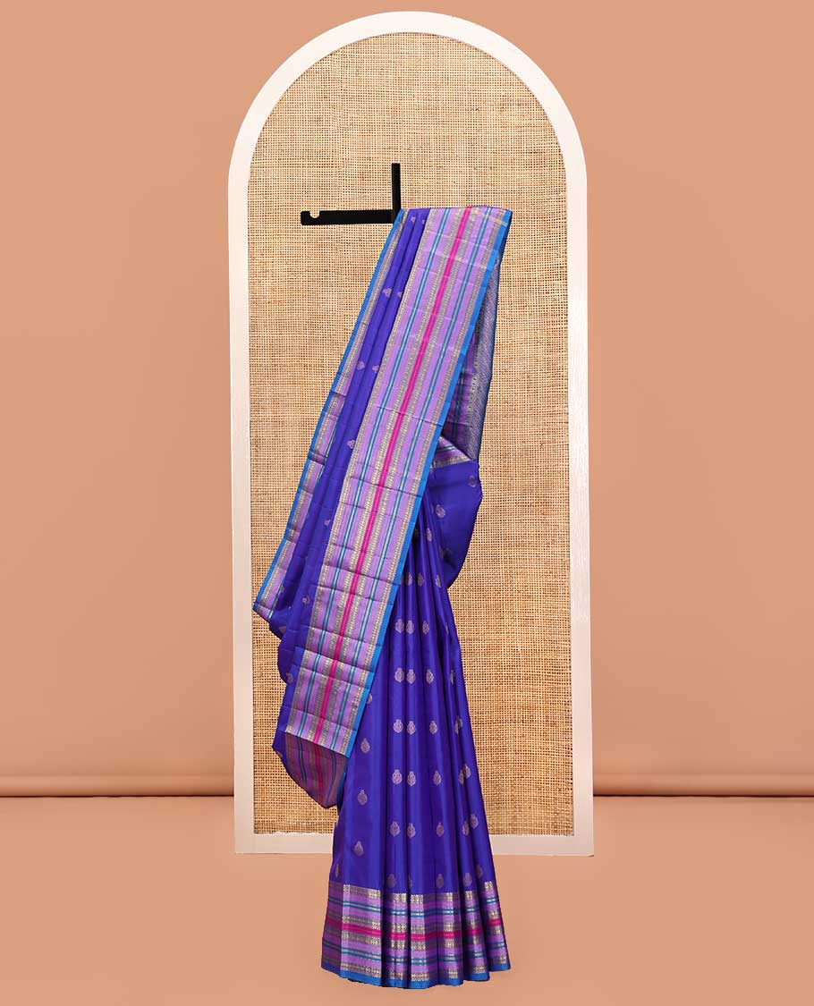 Violet and Mayil Blue Vasundhara Silk Saree, Subtly Sparkled with Zari Buttas All Over Its Body, Highlighted by Self-Border of Thilakam Mokku, Rudraksham, Muthu, and Mayil Kann Designs, Diagonally Striped Pallu, and Paired with a Matching Blouse