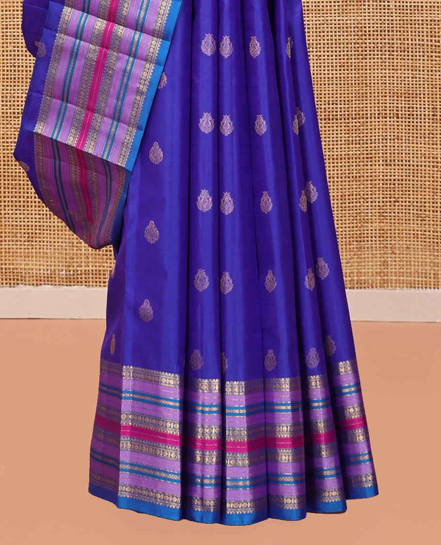 Violet and Mayil Blue Vasundhara Silk Saree, Subtly Sparkled with Zari Buttas All Over Its Body, Highlighted by Self-Border of Thilakam Mokku, Rudraksham, Muthu, and Mayil Kann Designs, Diagonally Striped Pallu, and Paired with a Matching Blouse