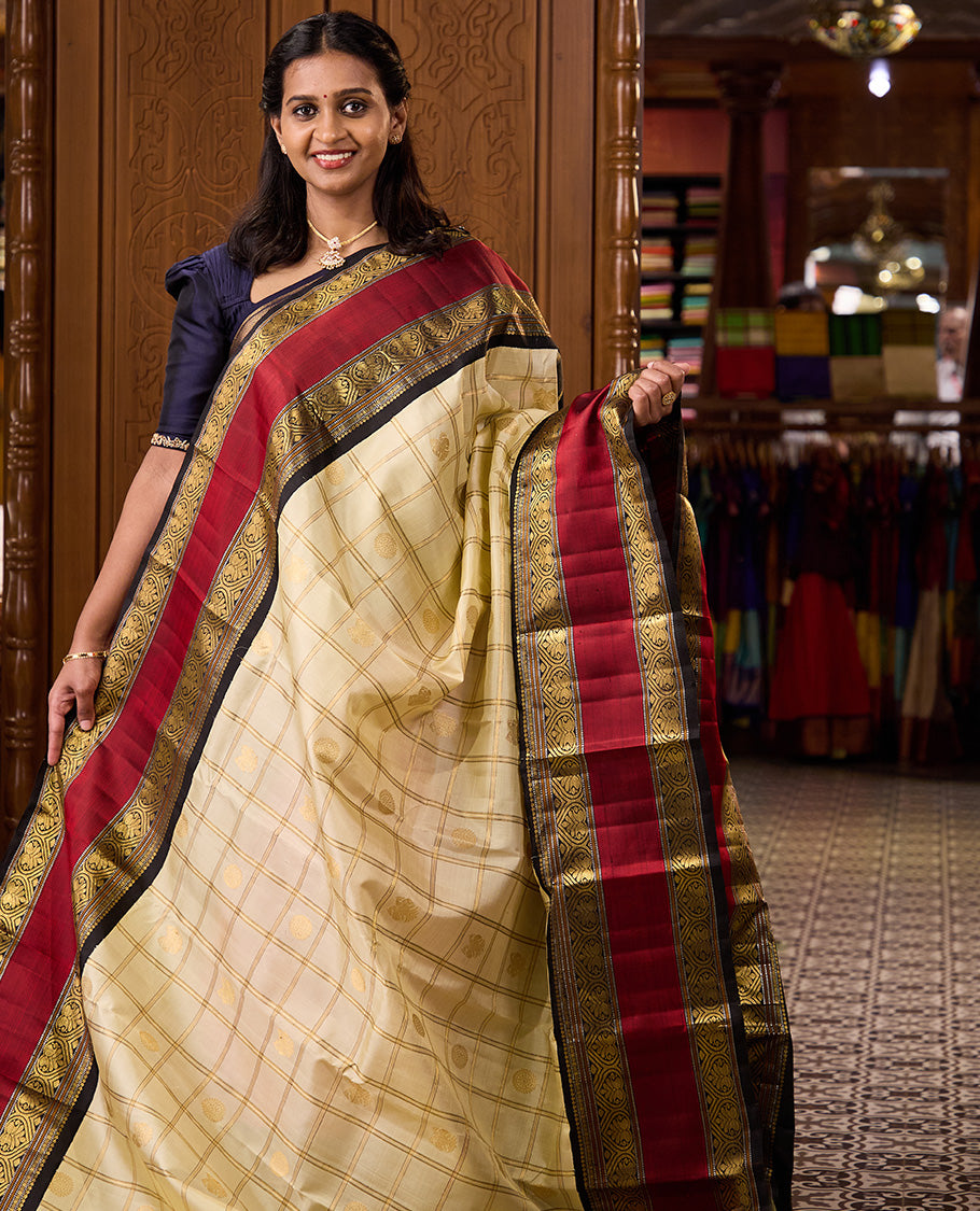 Cream iruthalai pakshi, and chakram buttas enclosed zari checked Kanchipuram silk saree, contrast rettai pettu border of salngai, muthu, and jadai nagam designs