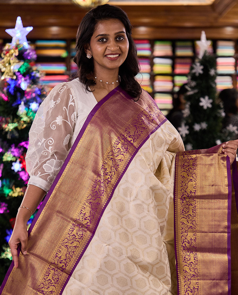 Cream jacquard silk saree, contrast vanasingaram style border of thilakam mokku, kodi visiry, mayil, maan, and yaanai designs, and intricate pallu