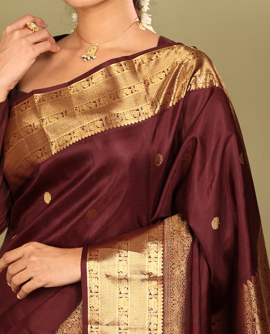 Brown Kanchipuram Silk Saree, Adorned with Zari Buttas, a Zari Border of Iruthalai Pakshi, Thilakam, Kathir, Mayil, Yaanai, and Mayil Kann Designs, Jaal Pallu, and a Matching Blouse