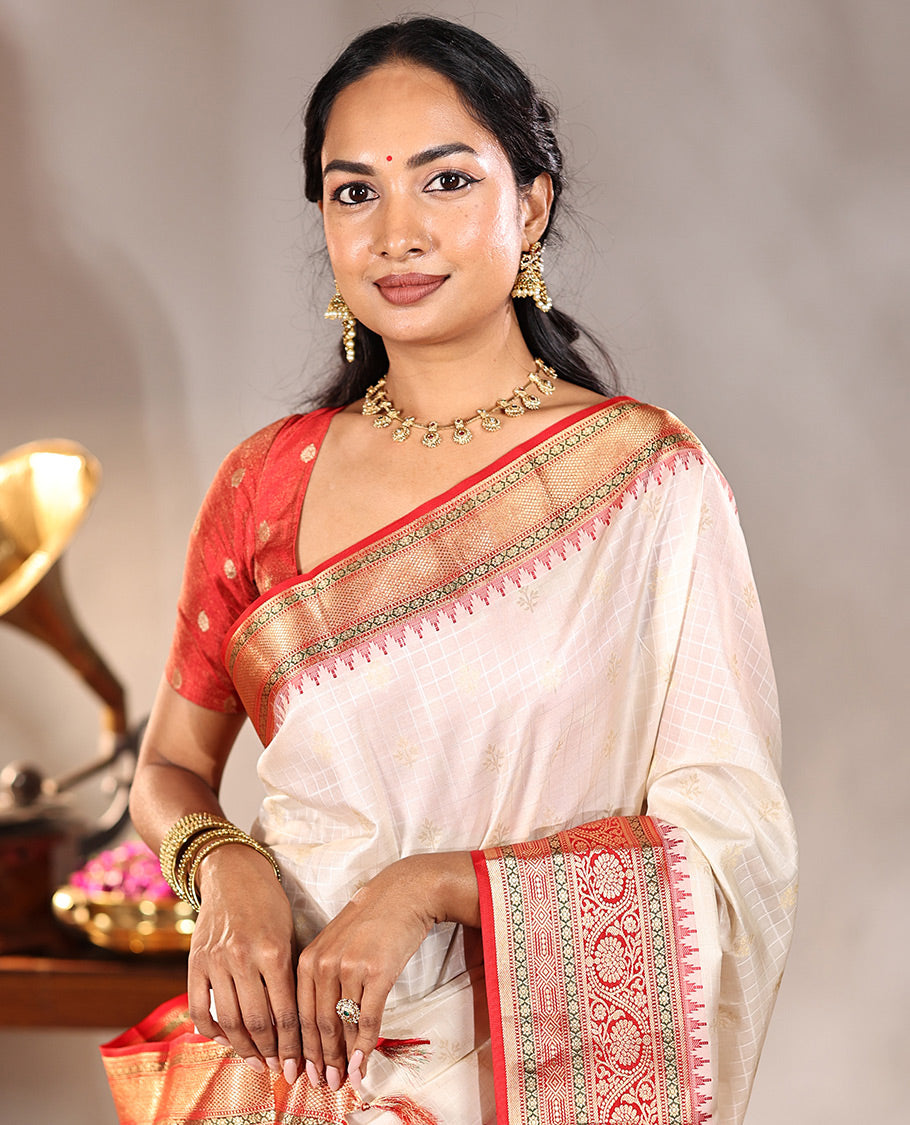 Cream Vasundhara Silk Saree, Subtly Sparkled with Buttas And Checks On Its Body, Complemented by Captivating Contrast Border of Thazampoo Rekku, Muthu, Banaras, and Kodi Visiry Designs, Pallu Steeped with Manga Designs, And Paired with a Contrast Blouse