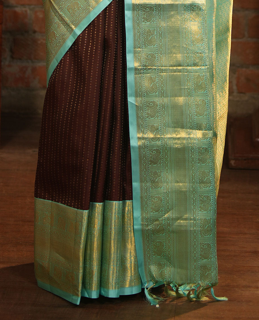 Brown Vasundhara Silk Saree Delicately Woven with Zari Buttas, Highlighted with a Contrast Border of Cross Kamalam, Mayil, Banaras, Yaanai, and Mayil Kann Designs, Pallu Grandly Woven with Jaal Designs, and Paired with a Contrast Blouse