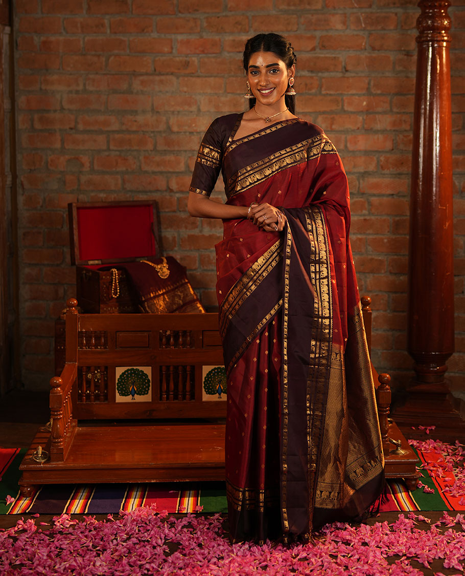Maroon Vasundhara Silk Saree Decorated with Zari Buttas All Over Its Body, Complemented by a Contrast Rettai Pettu Border Steeped with Yaanai Motifs, Richly Detailed Pallu of Jaal Designs, and Paired with a Contrast Zari Bordered Blouse