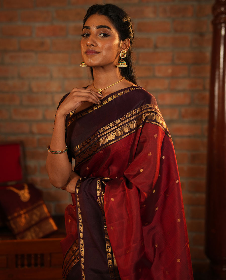 Maroon Vasundhara Silk Saree Decorated with Zari Buttas All Over Its Body, Complemented by a Contrast Rettai Pettu Border Steeped with Yaanai Motifs, Richly Detailed Pallu of Jaal Designs, and Paired with a Contrast Zari Bordered Blouse