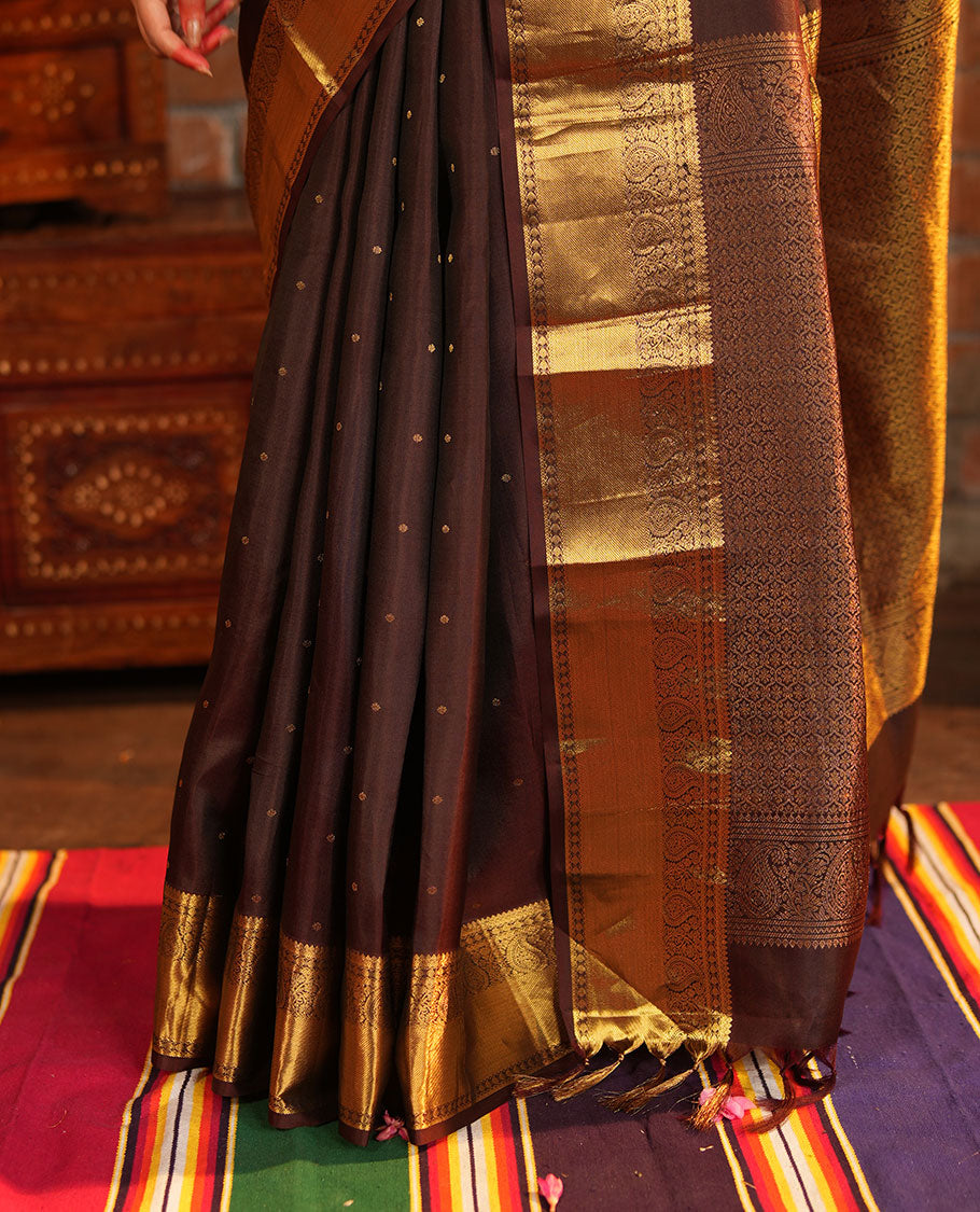 Brown Vasundhara Silk Saree Beautified with Zari Buttas All Over Its Body, Gleamed Up with a Zari Border of Thilakam Mokku, Kathir, Rudraksham, and Arumbu Manga Designs, Majestically Detailed Pallu of Jaal Designs, and Comes with a Matching Blouse