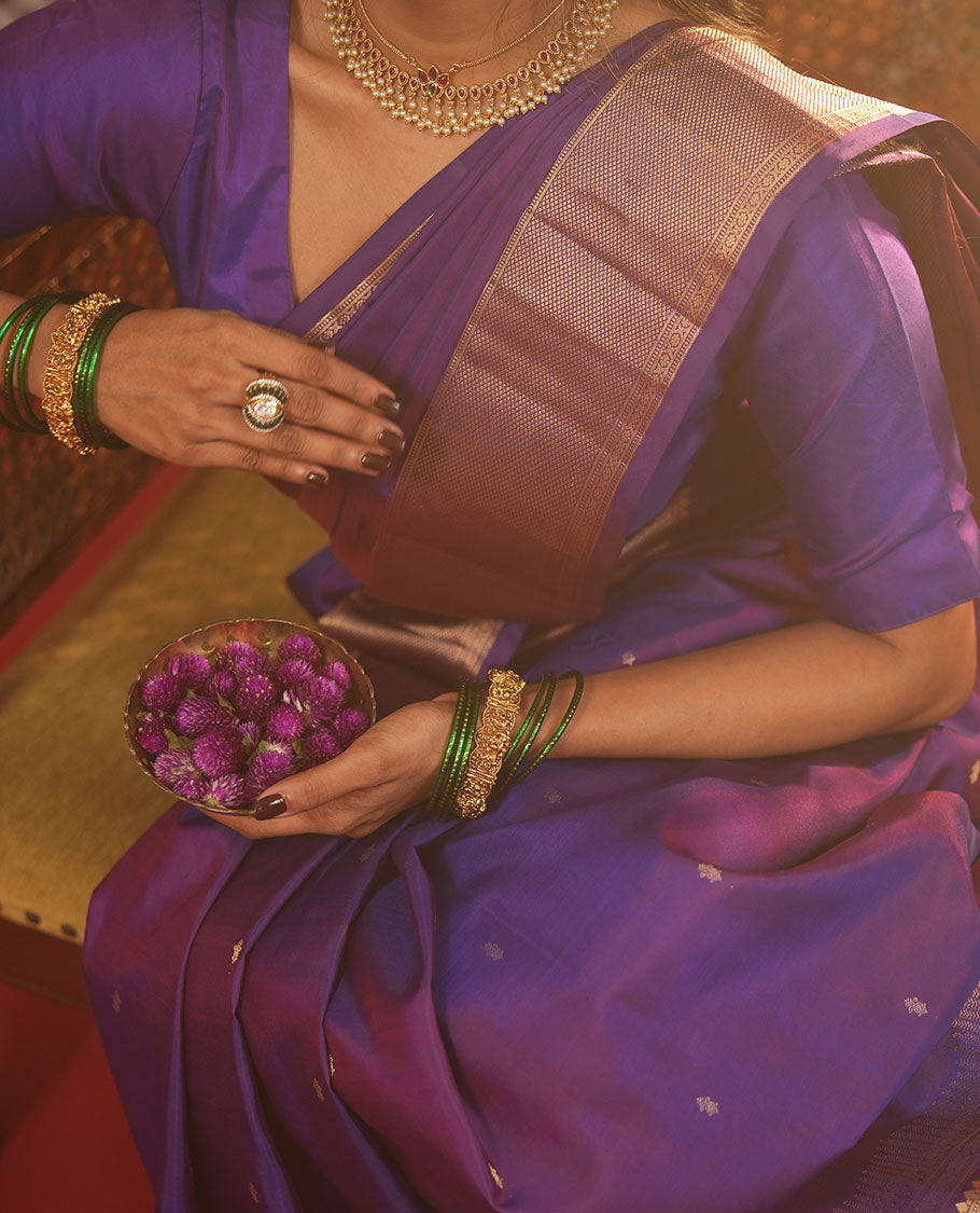 Violet Vasundhara Silk Saree Gracefully Embellished with Zari Buttas, Highlighted by a Zari Border Featuring Thilakam Mokku, Muthu, Cross Kamalam, and Mayil Kann Designs, Elegantly Embellished Pallu, and Paired with a Matching Blouse