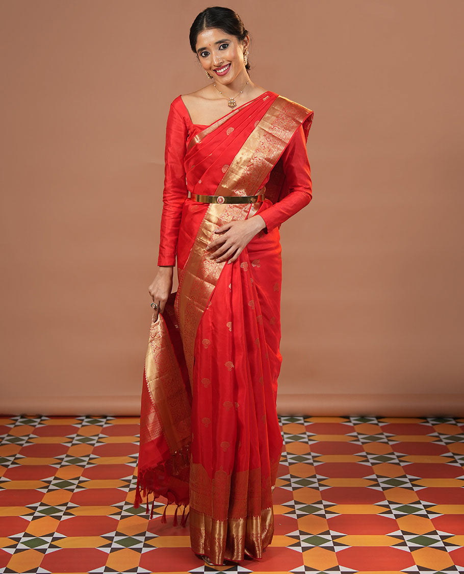 Red Vasundhara Silk Saree Traditionally Decked Up with Zari Buttas and Mamallapuram Temple Motifs, Highlighted by a Zari Border of Salangi, Muthu, Banaras, Mayil, and Lavangam Designs, Gracefully Embellished Pallu, and a Matching Blouse