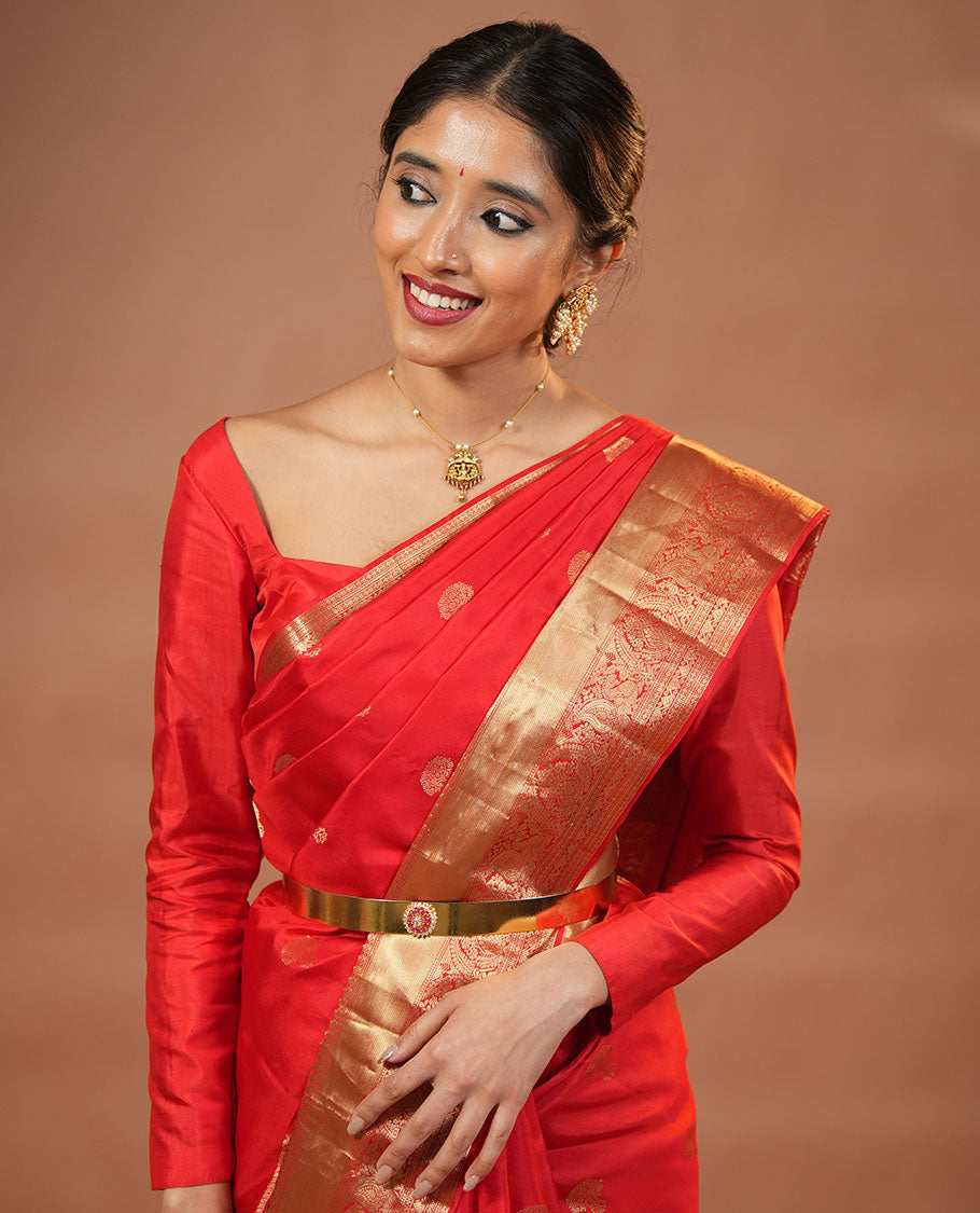 Red Vasundhara Silk Saree Traditionally Decked Up with Zari Buttas and Mamallapuram Temple Motifs, Highlighted by a Zari Border of Salangi, Muthu, Banaras, Mayil, and Lavangam Designs, Gracefully Embellished Pallu, and a Matching Blouse