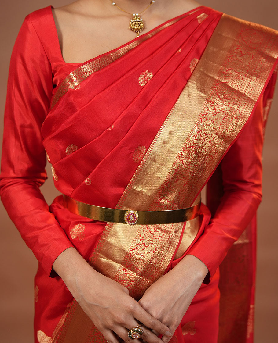 Red Vasundhara Silk Saree Traditionally Decked Up with Zari Buttas and Mamallapuram Temple Motifs, Highlighted by a Zari Border of Salangi, Muthu, Banaras, Mayil, and Lavangam Designs, Gracefully Embellished Pallu, and a Matching Blouse