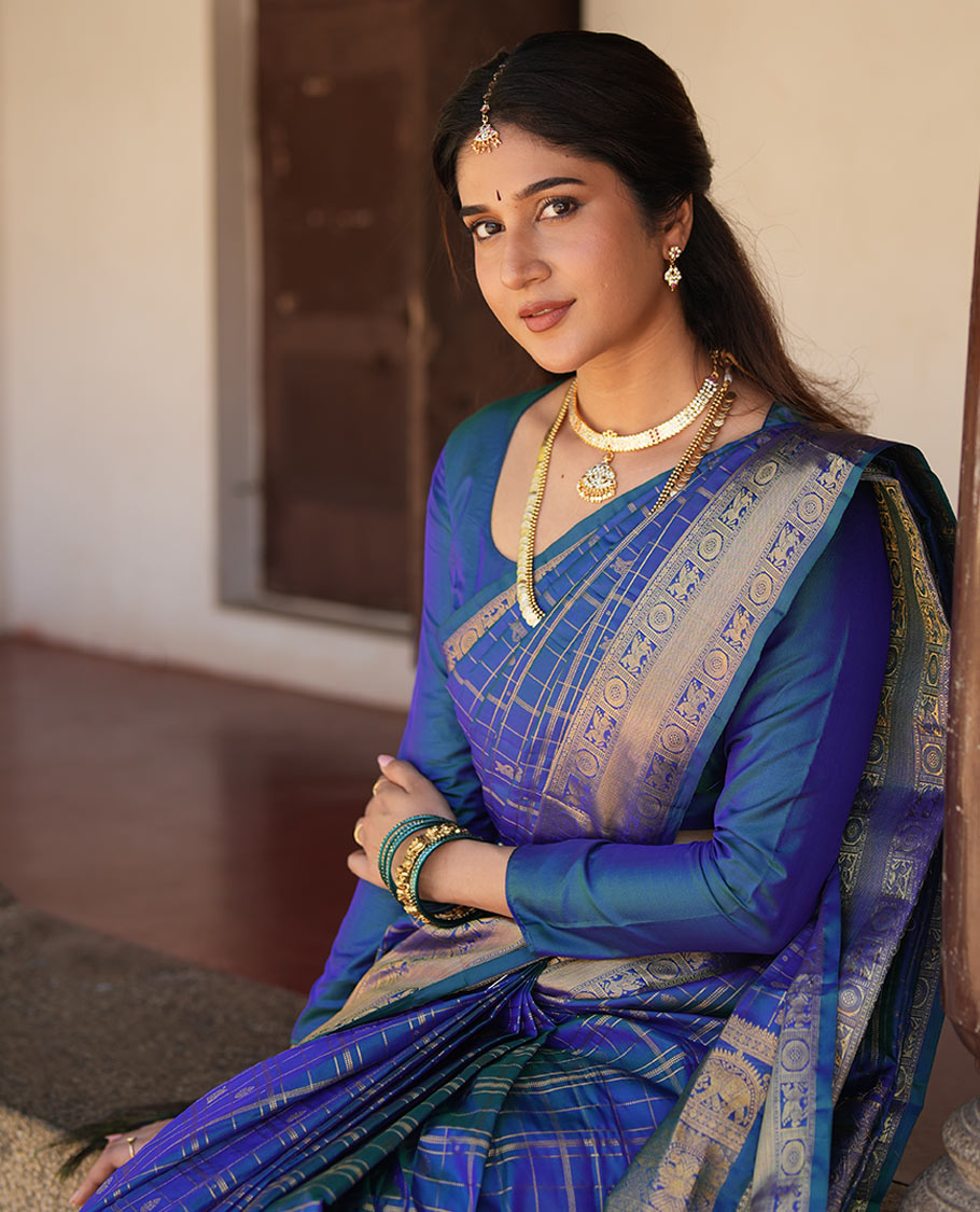 Blue Zari Buttas Enclosed in a Checked Vasundhara Silk Saree, Zari Border Adorned with Kuthirai and Chakram Designs, and Pallu Features Intricate Designs in Zari