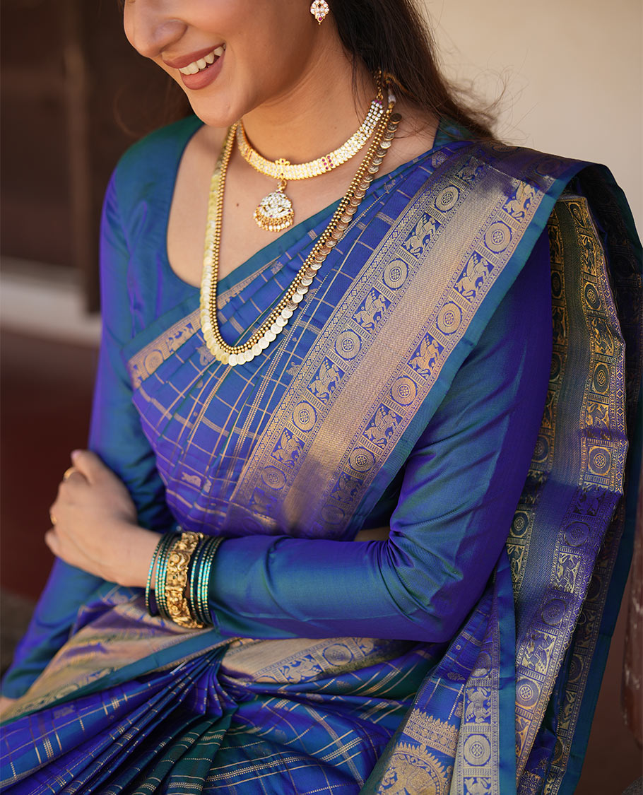 Blue Zari Buttas Enclosed in a Checked Vasundhara Silk Saree, Zari Border Adorned with Kuthirai and Chakram Designs, and Pallu Features Intricate Designs in Zari