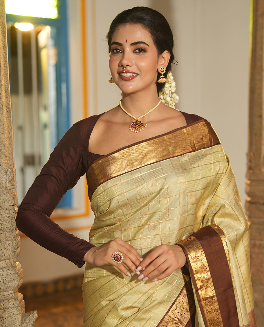Pale Green Vasundhara Silk Saree, Enriched with Zari Buttas Enclosed Checks All Over Its Body, Complemented by a Contrast Rettai Pettu Border of Muthu, Banaras, and Iruthalai Pakshi Designs, a Grand Pallu, and Paired with a Contrast Blouse