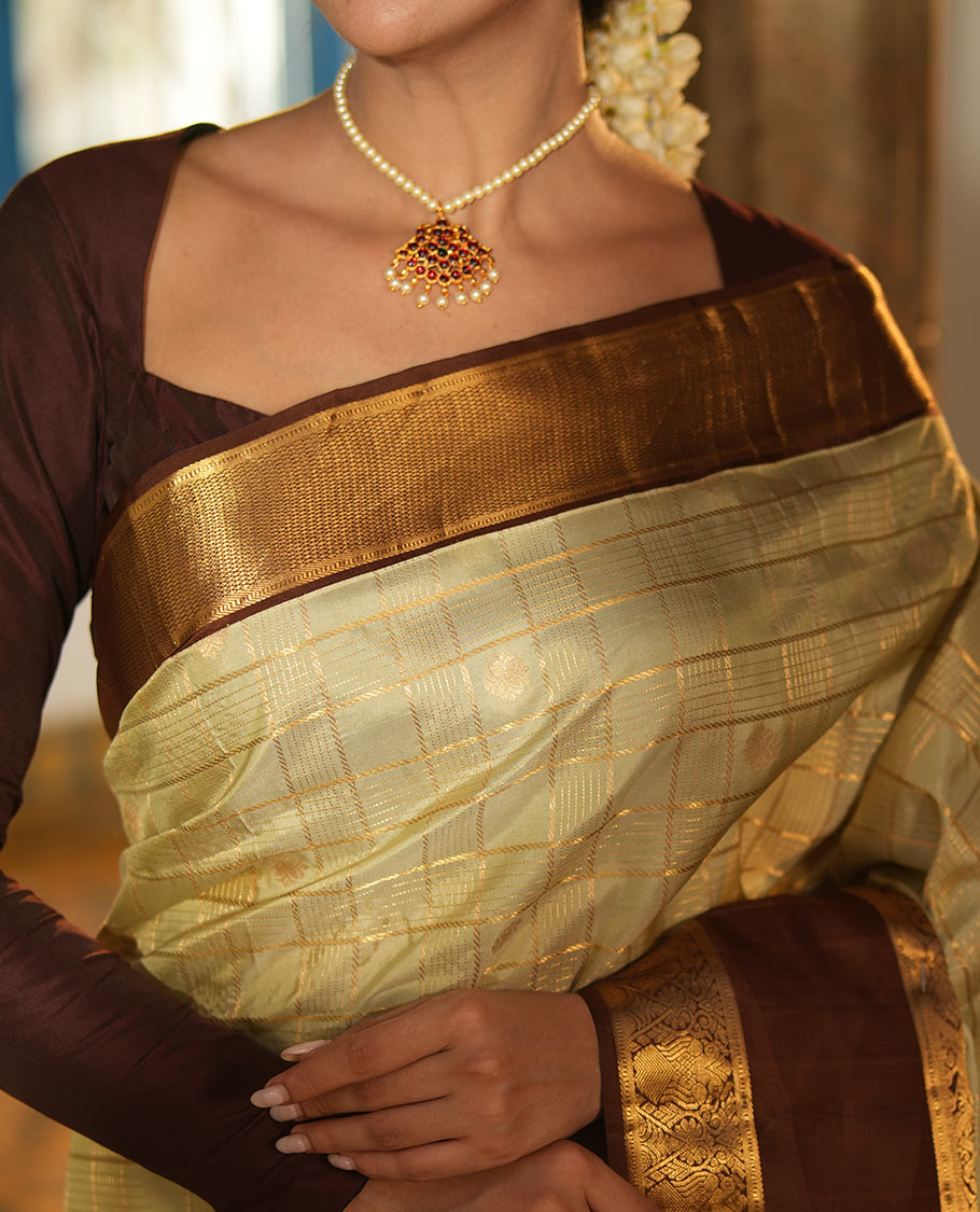 Pale Green Vasundhara Silk Saree, Enriched with Zari Buttas Enclosed Checks All Over Its Body, Complemented by a Contrast Rettai Pettu Border of Muthu, Banaras, and Iruthalai Pakshi Designs, a Grand Pallu, and Paired with a Contrast Blouse