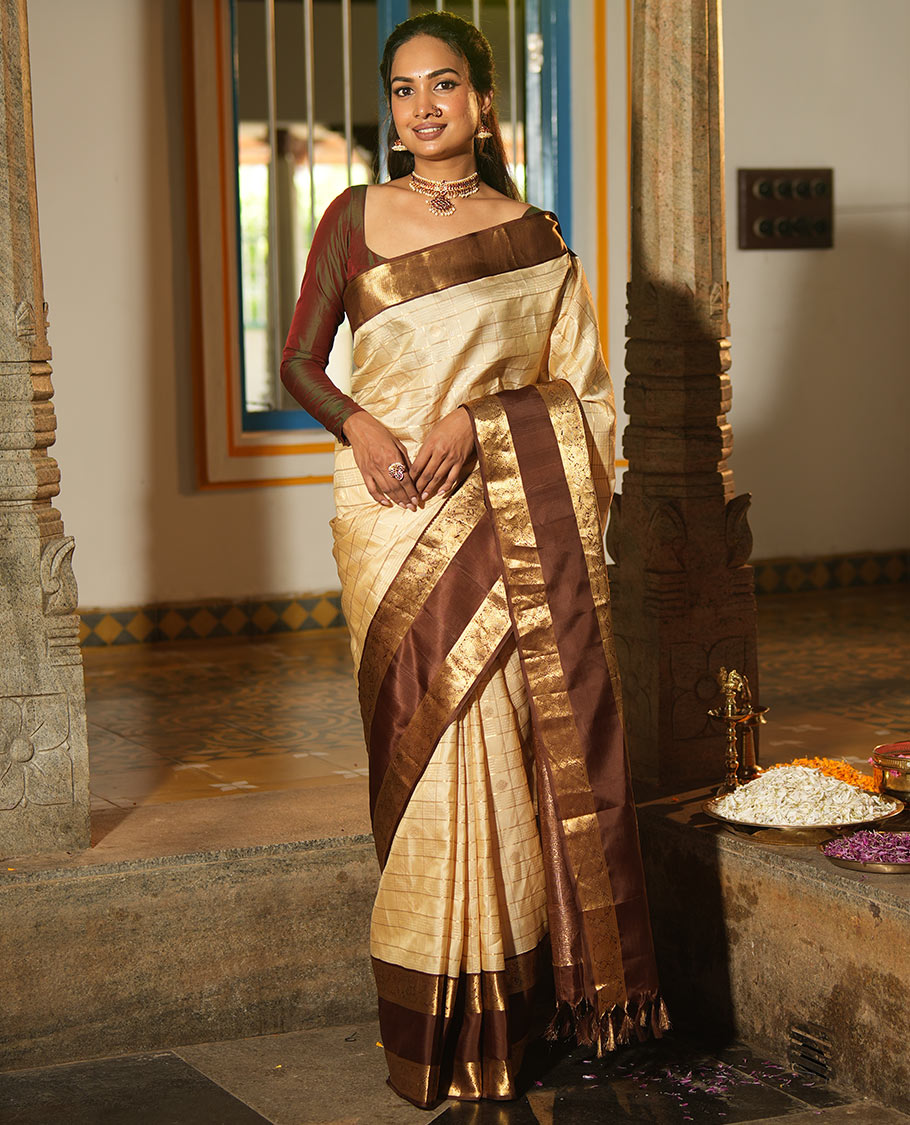 Cream Vasundhara Silk Saree, Enthralled with Zari Buttas Enclosed Checks All Over Its Body, Complemented by a Contrast Rettai Pettu Border of Muthu, Banaras, and Iruthalai Pakshi Designs, a Grand Pallu, and Paired with a Contrast Blouse