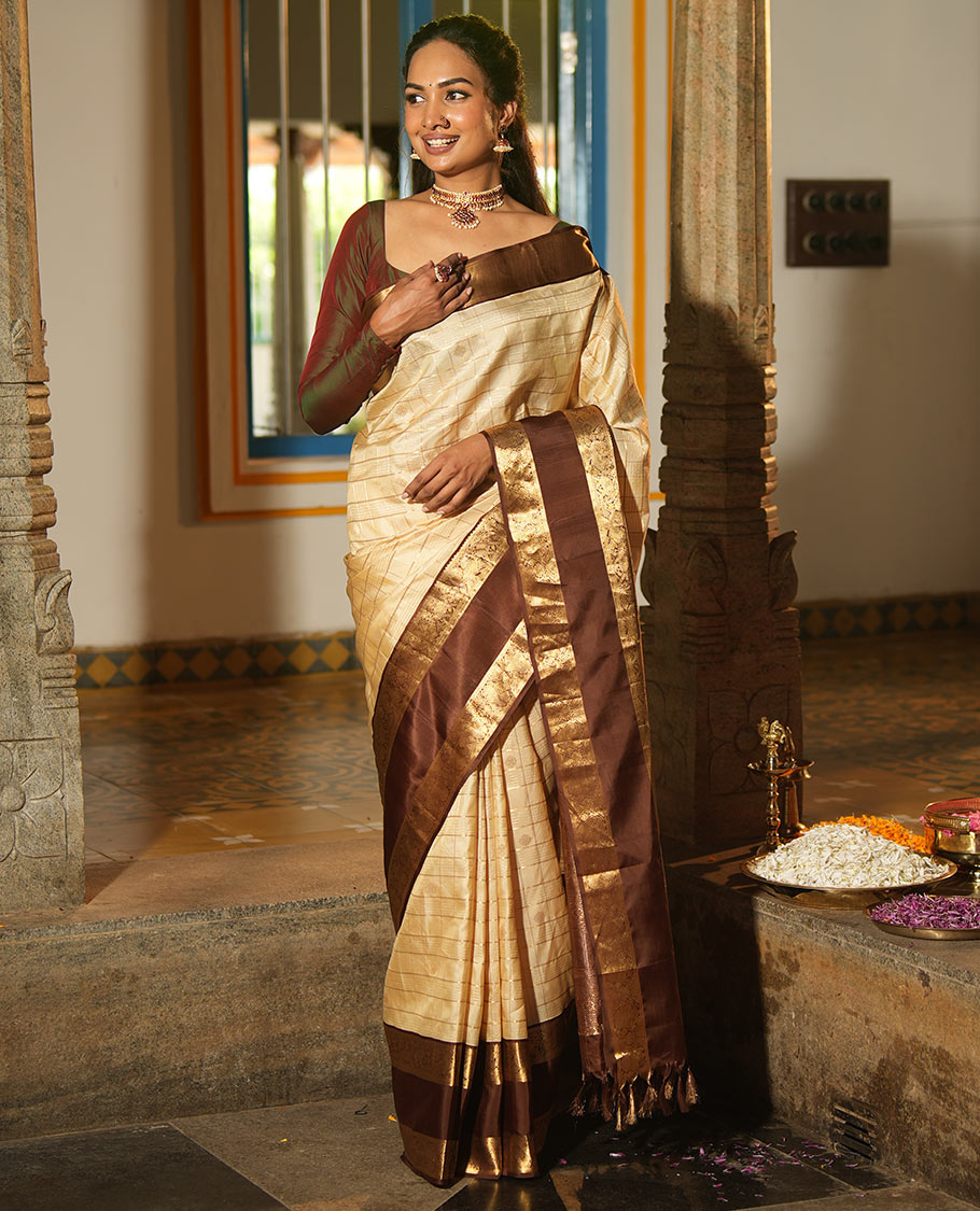 Cream Vasundhara Silk Saree, Enthralled with Zari Buttas Enclosed Checks All Over Its Body, Complemented by a Contrast Rettai Pettu Border of Muthu, Banaras, and Iruthalai Pakshi Designs, a Grand Pallu, and Paired with a Contrast Blouse