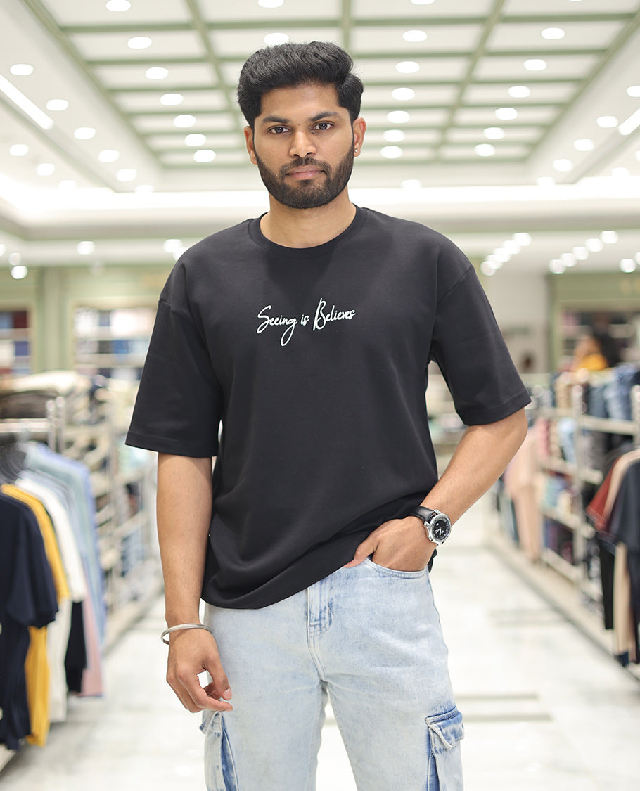 Black Glow in the Dark Cotton-Blended T-Shirt, Bedecked with Colorful Cartoon Motifs Print, Comes with a Crew Neck, Half-Sleeves, Oversized Fit, and Long Length
