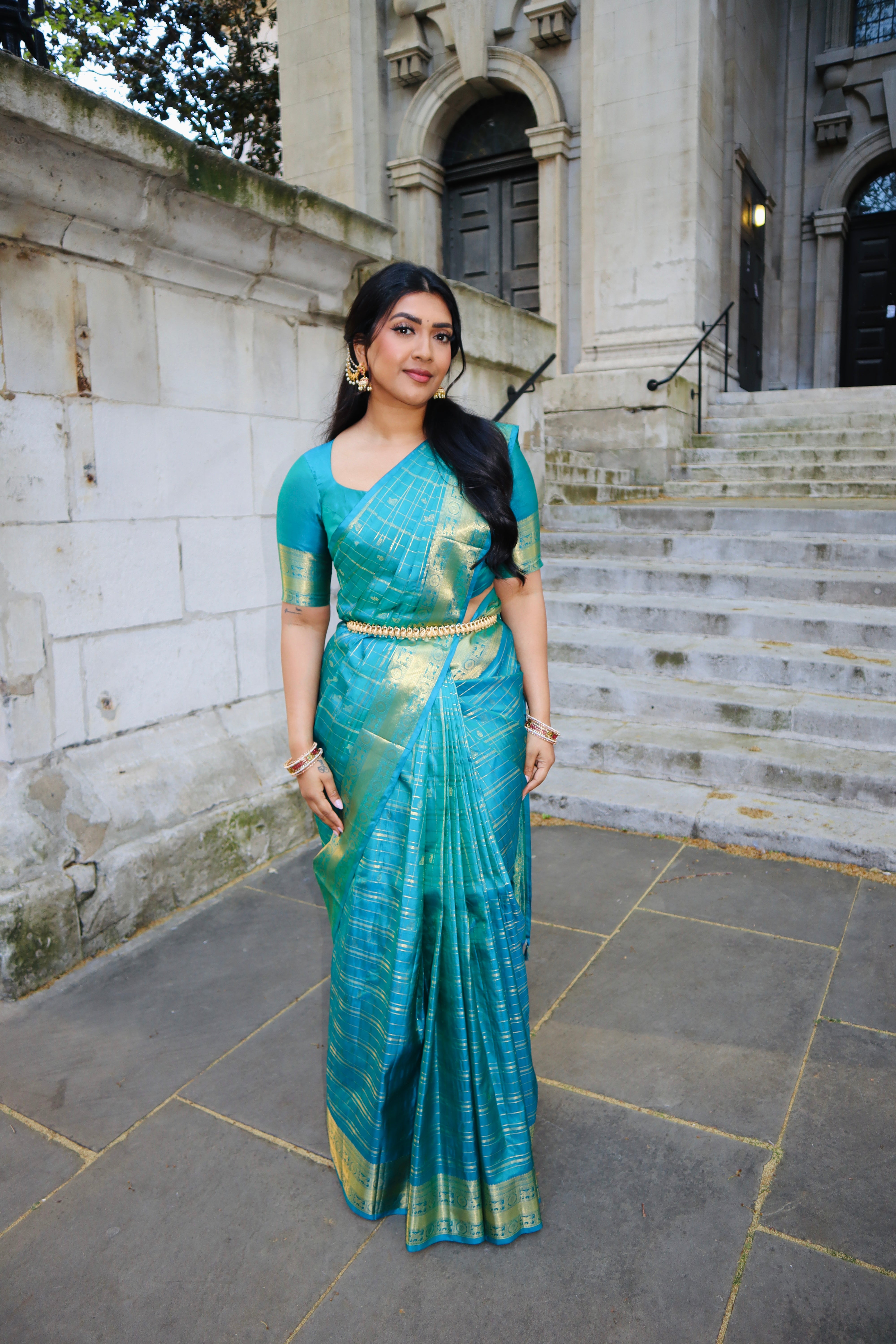 Neelambhari - Peacock Blue Vasundhara Silk Saree Gleamed Up with Zari Buttas Enclosed in Zari Checks, Featuring a Zari Border of Kuthirai and Chakra Designs, Rich Zari Pallu, with a Matching Blouse