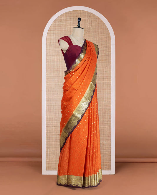Orange Mysore Silk Saree Subtly Sparkled with Embossed Weave and Zari Buttas All Over Its Body, Complemented by a Contrast Zari Border of Scallop Designs, a Gleaming Pallu of Floral Jaal Design, and a Contrast Blouse