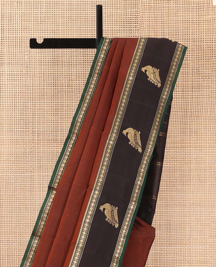 Rust plain Kanchipuram silk saree, contrast border of rekku, muthu, rudraksham and mayil, and zari striped pallu