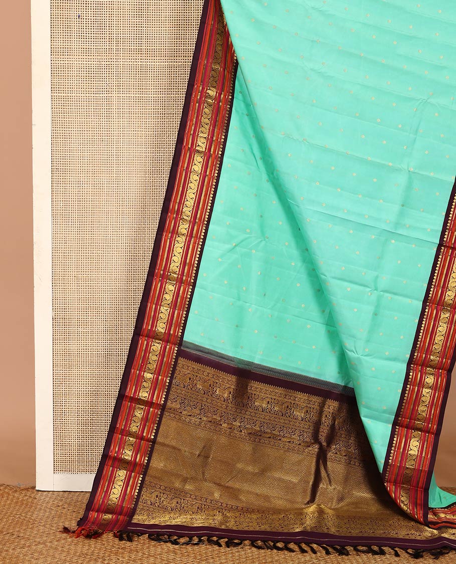 Turquoise zari buttas Kanchipuram silk saree, contrast korvai border of salangai, nuli nagam, kathir, and dhavanai manga kodi designs, and mayil kann woven pallu