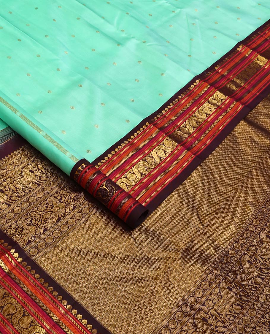 Turquoise zari buttas Kanchipuram silk saree, contrast korvai border of salangai, nuli nagam, kathir, and dhavanai manga kodi designs, and mayil kann woven pallu