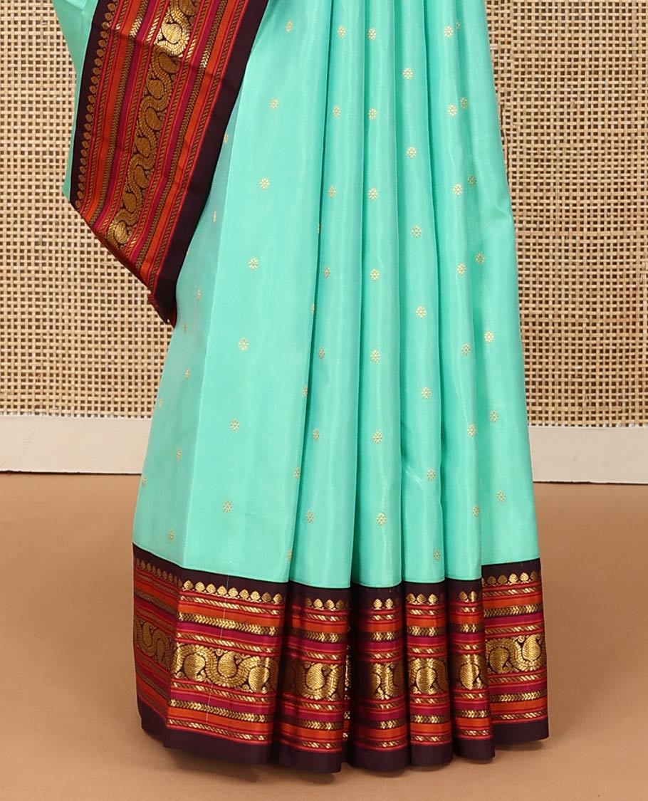 Turquoise zari buttas Kanchipuram silk saree, contrast korvai border of salangai, nuli nagam, kathir, and dhavanai manga kodi designs, and mayil kann woven pallu