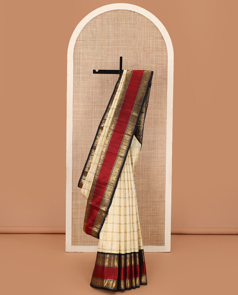 Cream iruthalai pakshi, and chakram buttas enclosed zari checked Kanchipuram silk saree, contrast rettai pettu border of salngai, muthu, and jadai nagam designs