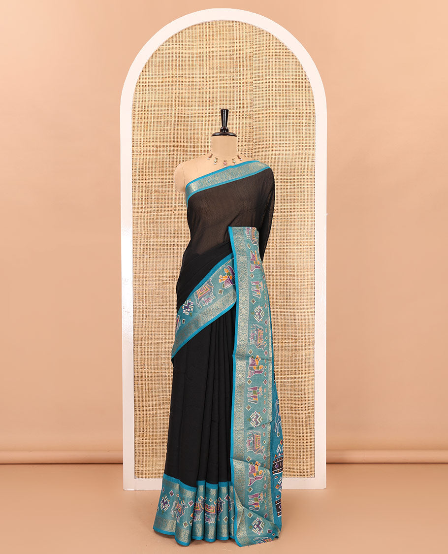 Black embossed moss chiffon saree, contrast zari and colorfully printed border and pallu of human figurines and Pichwai cows, and embossed blouse