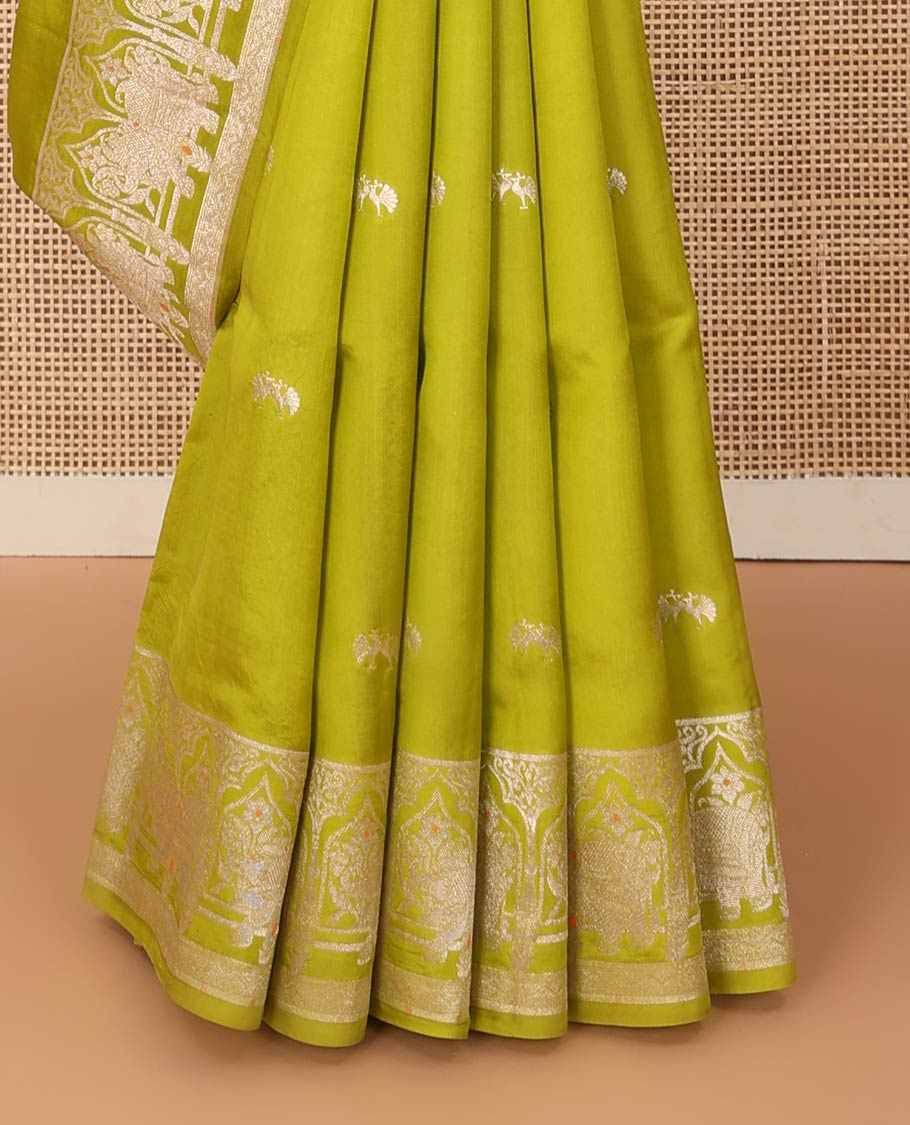 Parrot green zari buttas raw mango silk saree, Mughal border of elephant motifs, and pallu decked up with coconut tree, elephant, and butterflies