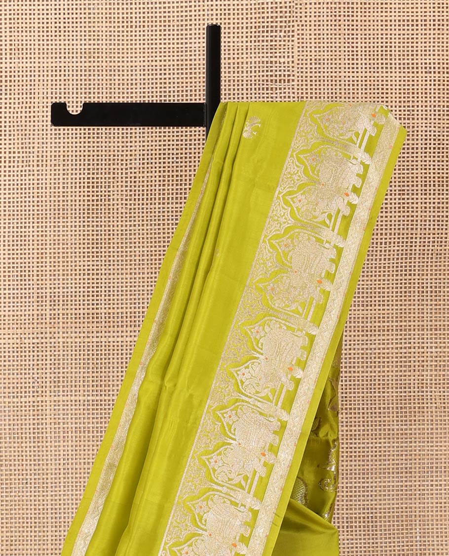 Parrot green zari buttas raw mango silk saree, Mughal border of elephant motifs, and pallu decked up with coconut tree, elephant, and butterflies