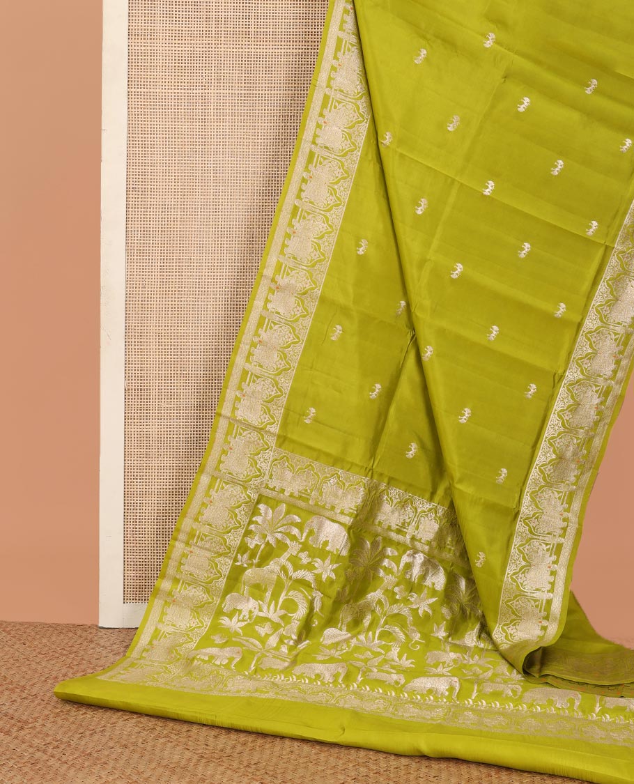 Parrot green zari buttas raw mango silk saree, Mughal border of elephant motifs, and pallu decked up with coconut tree, elephant, and butterflies