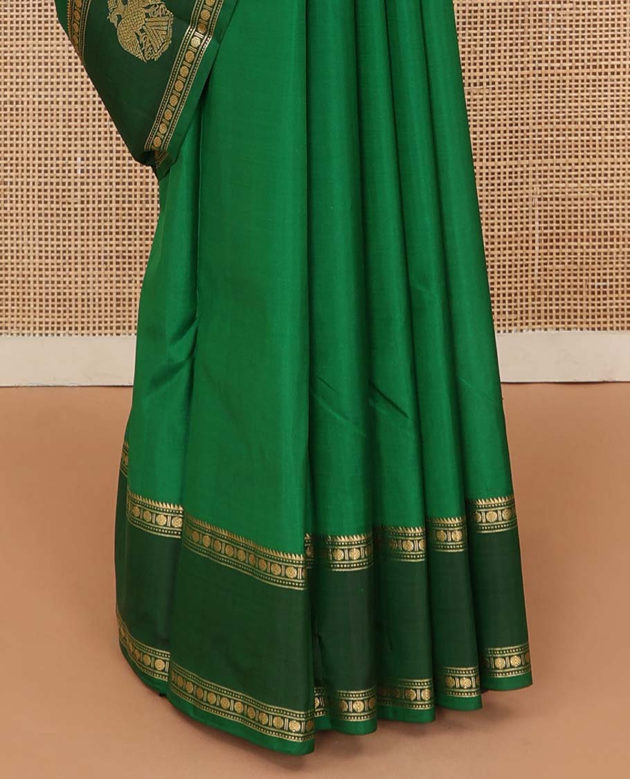 Green plain Kanchipuram silk saree, contrast border of rekku, muthu, rudraksham and iruthalai pakshi motifs, and zari striped pallu
