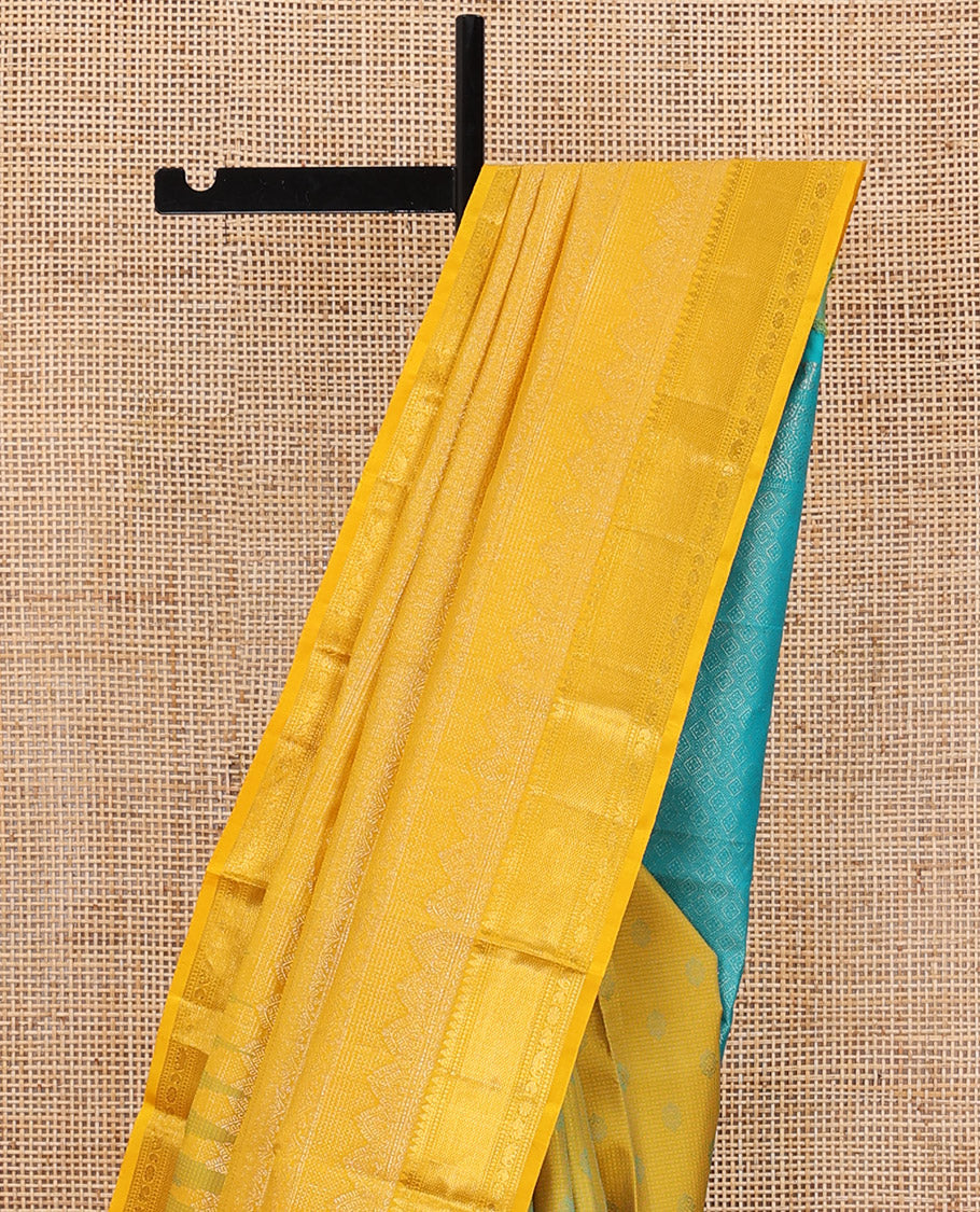 Yellow embossed silk saree, contrast border of thilakam mokku, muthu, ara bogudi, and kuyil kann, and jaal pallu