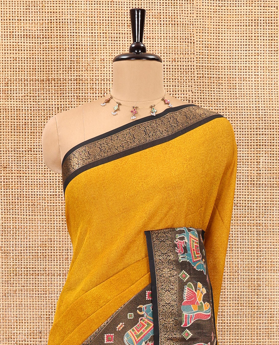 Mustard embossed moss chiffon saree, contrast zari and colorfully printed border and pallu of human figurines and Pichwai cows, and embossed blouse