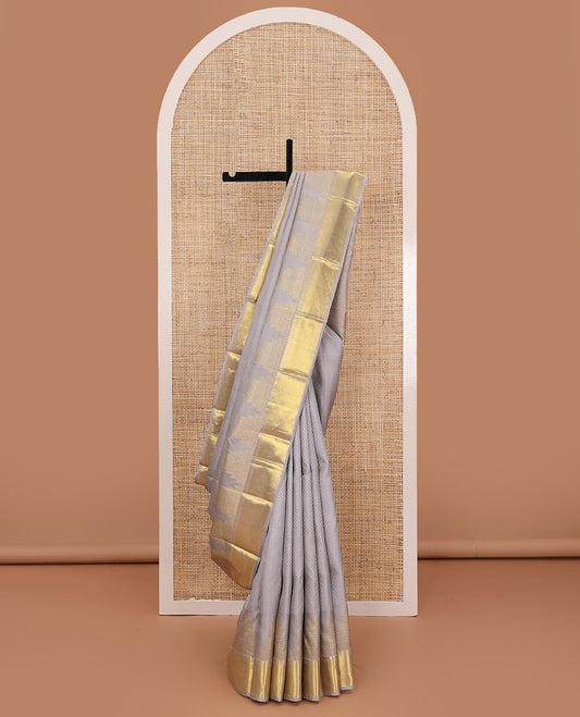 Grey embossed silk saree, thazampoo rekku golden zari border of thilakam mokku, muthu, and vanki designs, and zari rich jaal pallu