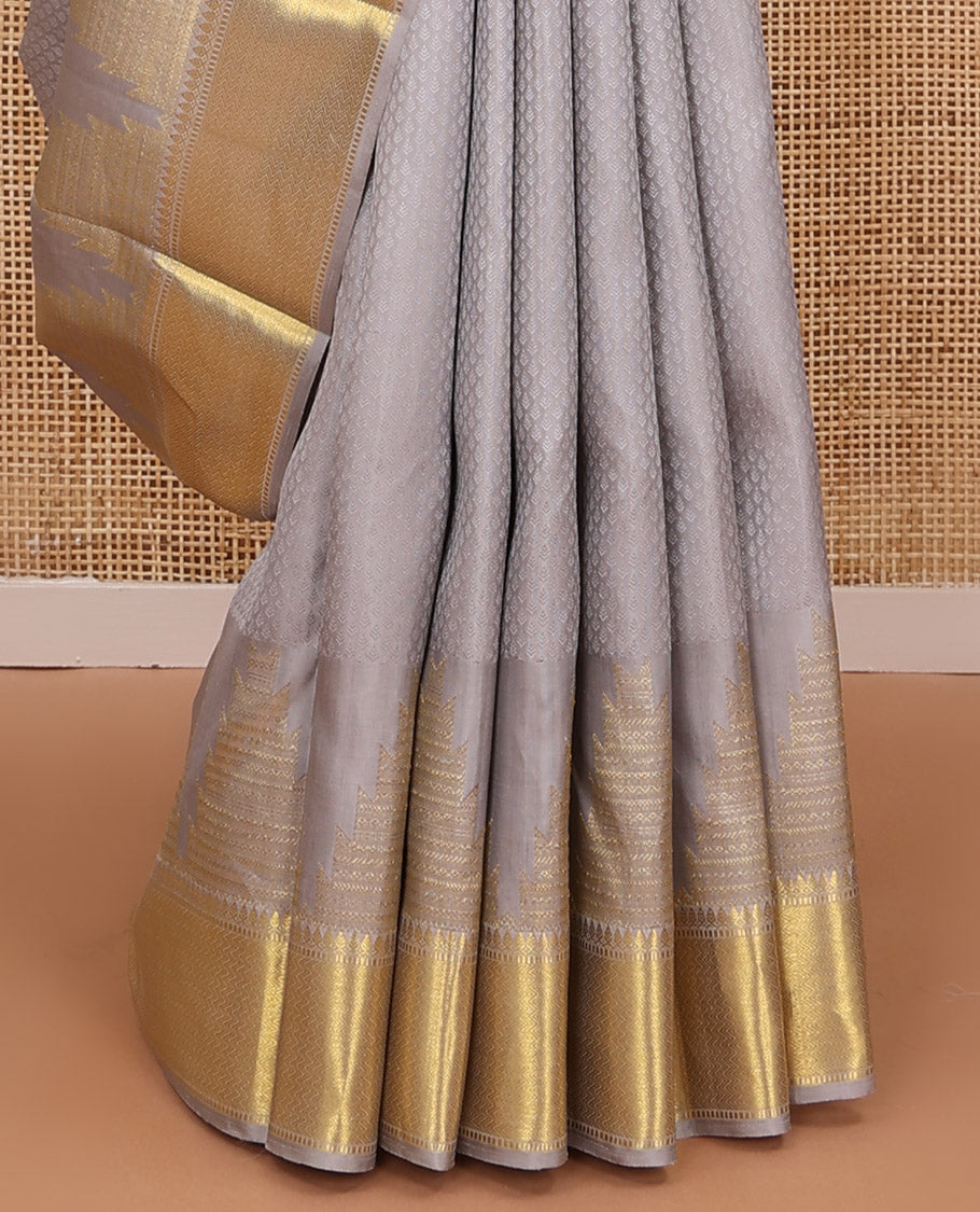 Grey embossed silk saree, thazampoo rekku golden zari border of thilakam mokku, muthu, and vanki designs, and zari rich jaal pallu