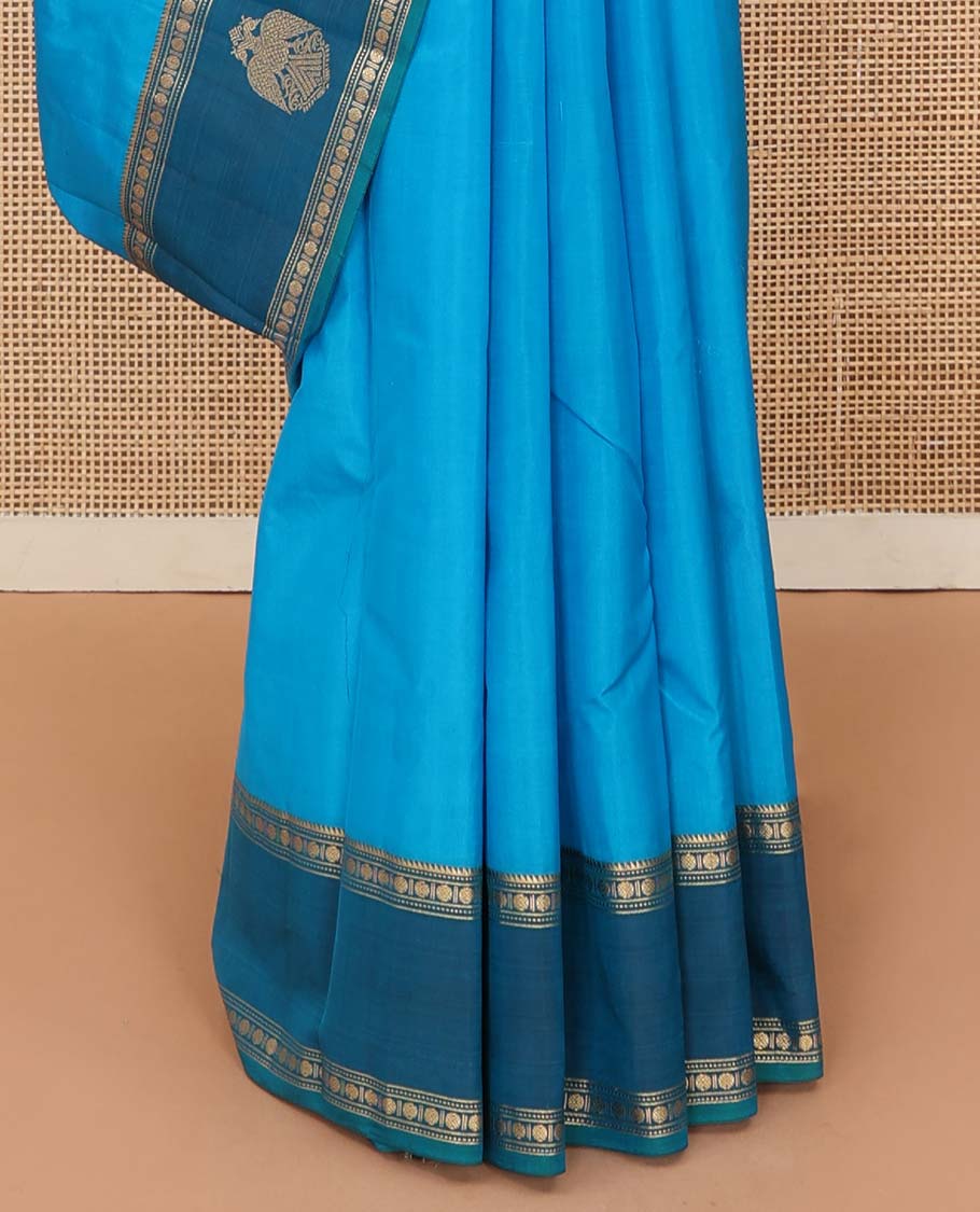 Blue plain Kanchipuram silk saree, contrast border of rekku, muthu, rudraksham and iruthalai pakshi motifs, and zari striped pallu